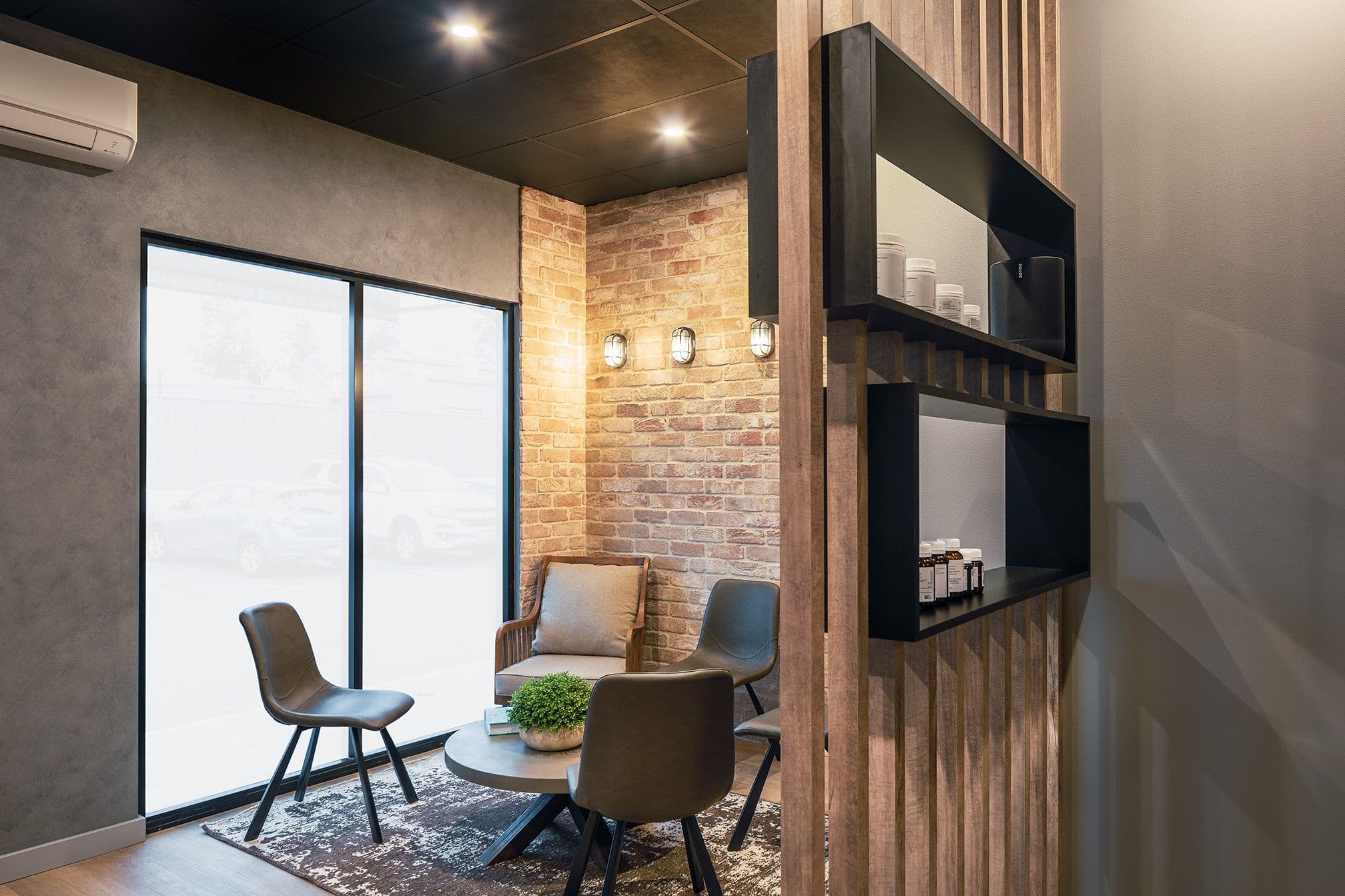 Daylight entering a chiropractic clinic waiting area with recycled brick, timber battens and black joinery by BHO Interiors